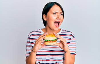 Beautiful young woman with short hair eating hamburger