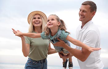 Happy family spending time together near sea on sunny summer day