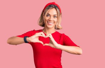 Smiling woman showing heart shape with her hands.