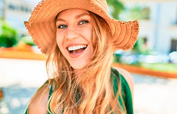 Young beautiful blonde woman on vacation wearing summer hat