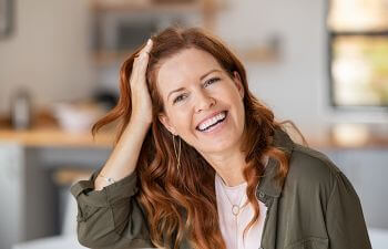 Smiling middle-aged woman combing her hair with her right hair.
