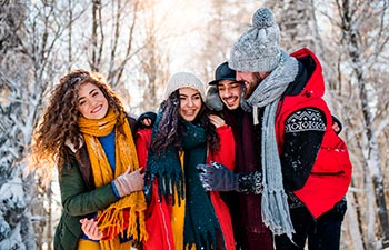 A group of young friends on a walk outdoors in snow in winter forest