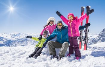 Family of four having fun while skiing in the mountains.