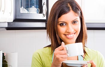young happy attractive woman drinking coffee in kitchen