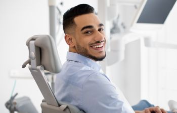 Satisfied man patient with a perfect smile sitting in in a dental chair.